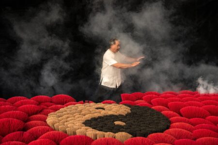 man practicing tai chi next to incenses forming ying yang symbol