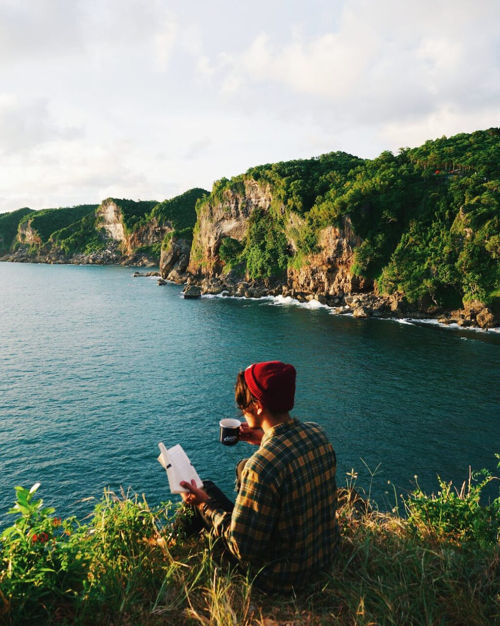 photo of person sitting on cliff edge