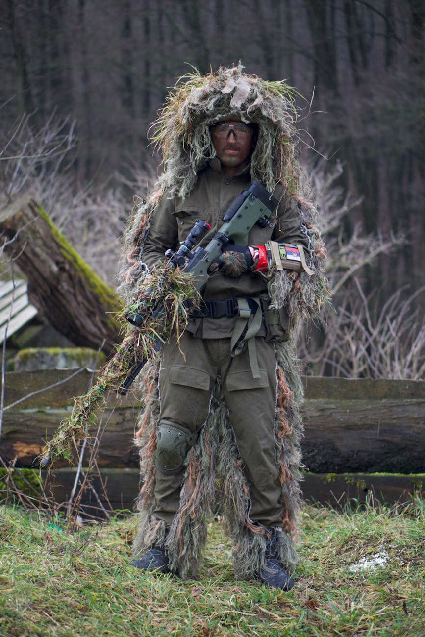 a person in green and brown camouflage jacket holding a machine gun