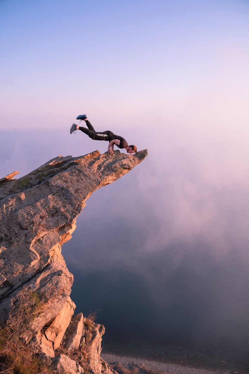 man exercising on top of cliff