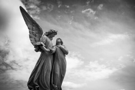 grayscale photography of angel statue under cloudy skies