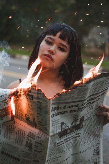 woman holding burning newspaper