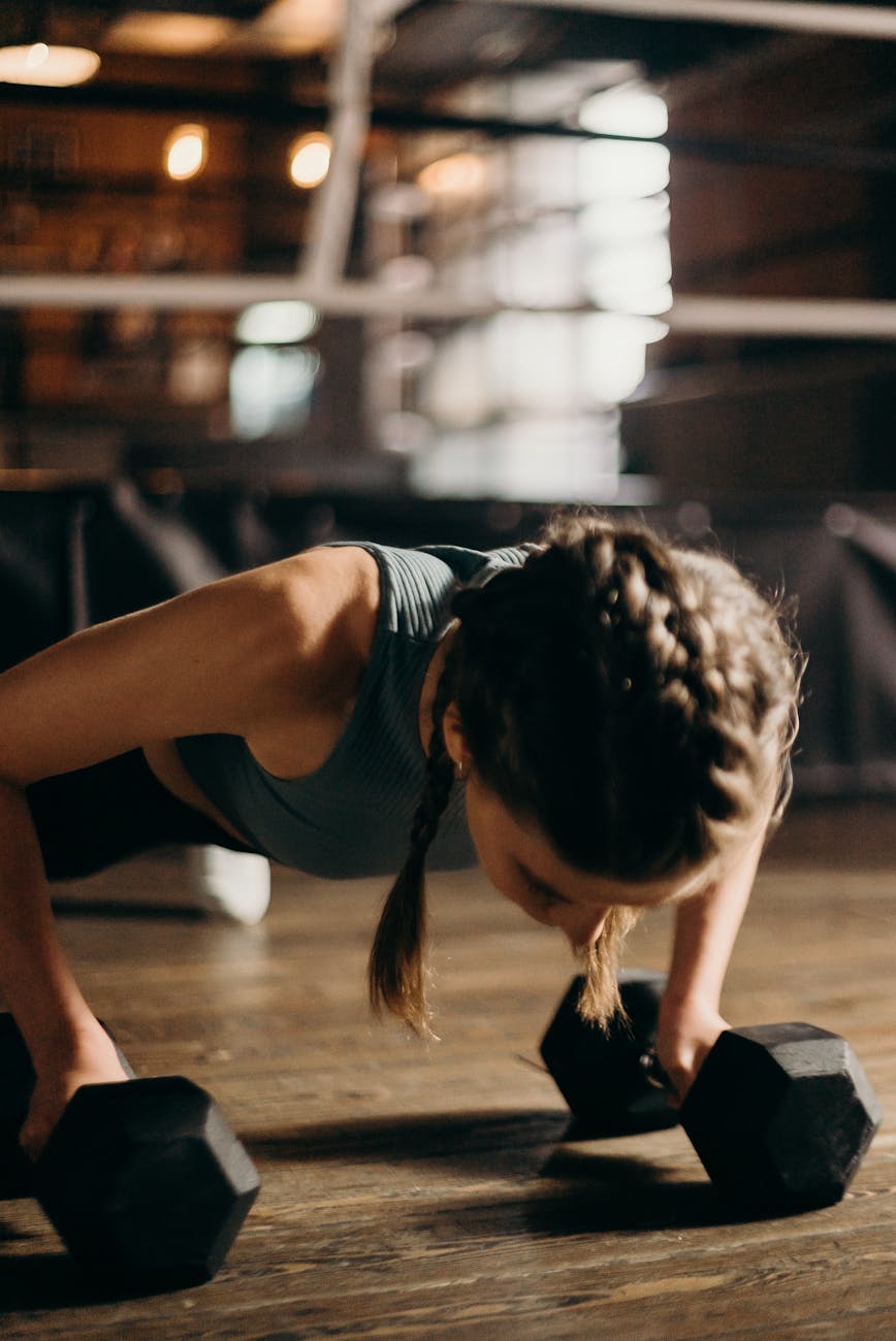 woman in white tank top and black shorts sitting on brown wooden floor