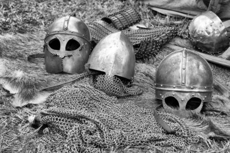 grayscale photography of chainmails and helmets on ground