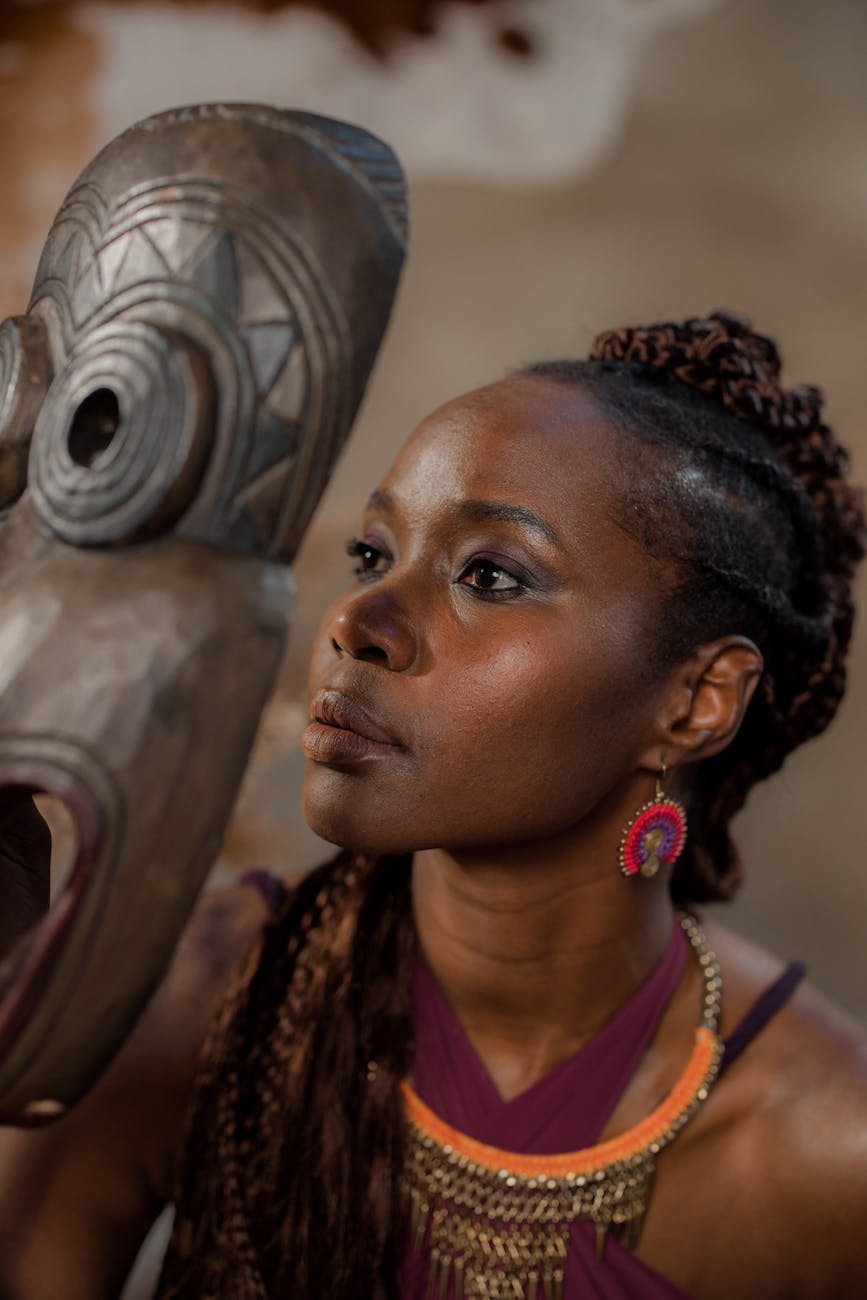 woman looking through a wooden hand carved african mask