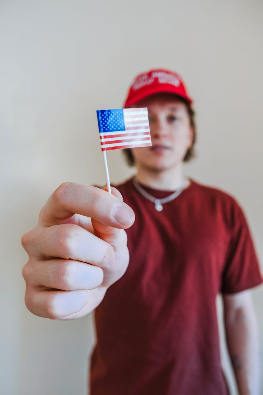man in red crew neck shirt holding us a flag