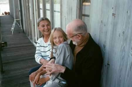 a child sitting on an elderly man s lap sitting beside an elderly woman