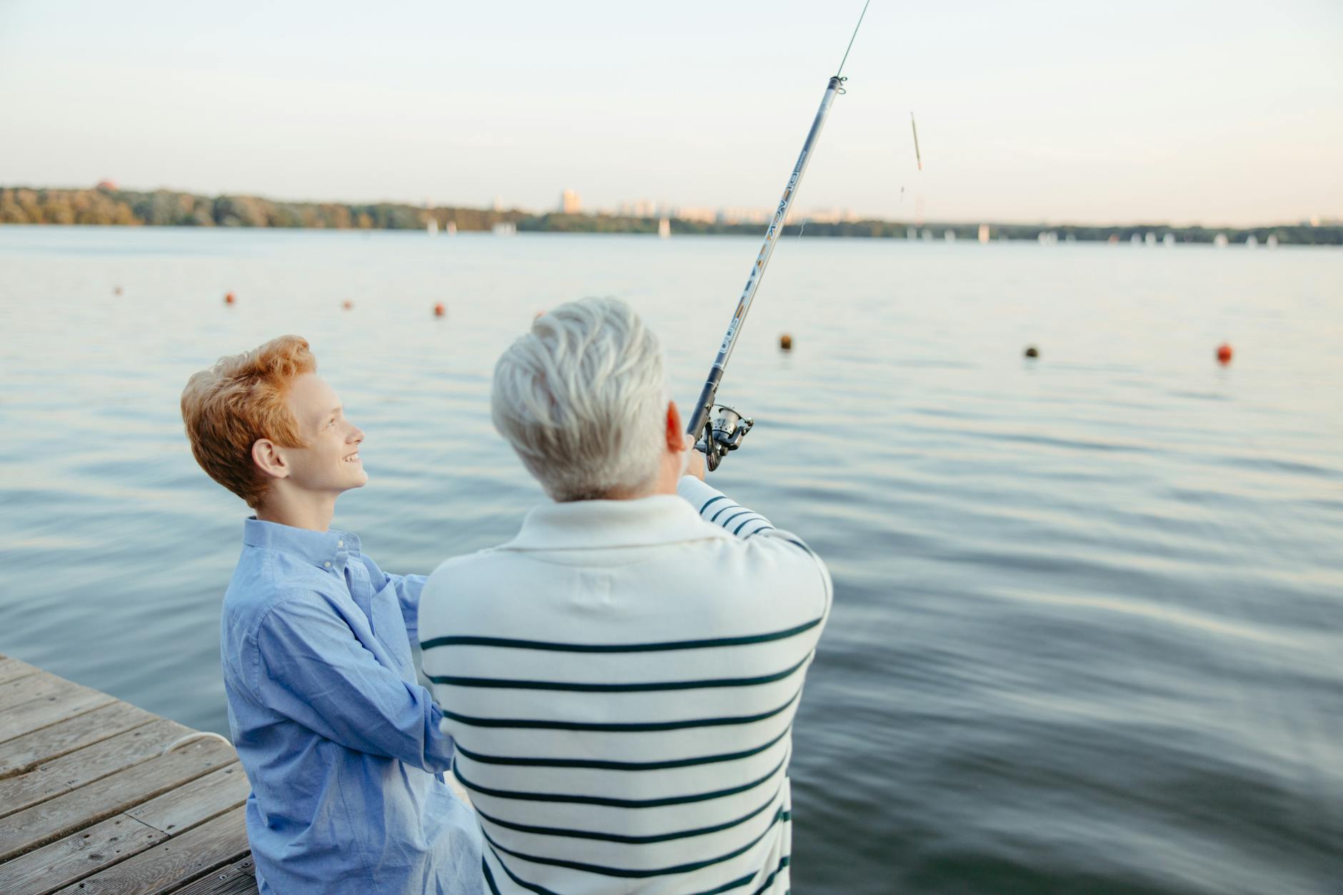 an elderly man and a boy fishing by the dock