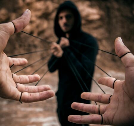 man pulling strings attached to another persons fingers