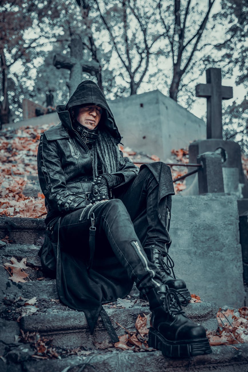 man in black leather jacket and black pants sitting on concrete stairs