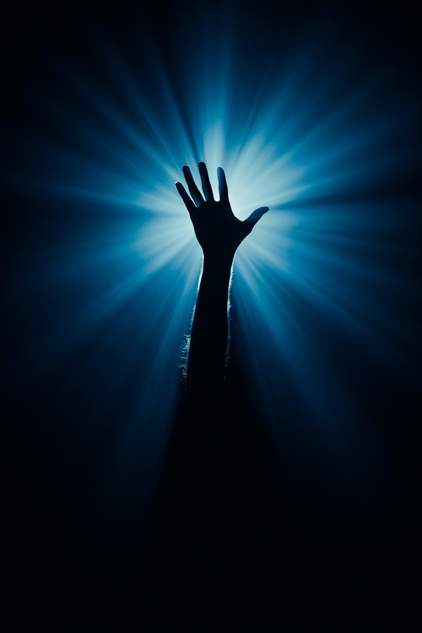 sillhouette of an open human hand lit with blue light