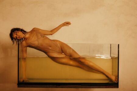photo of a young woman posing in a glass tank filled with water