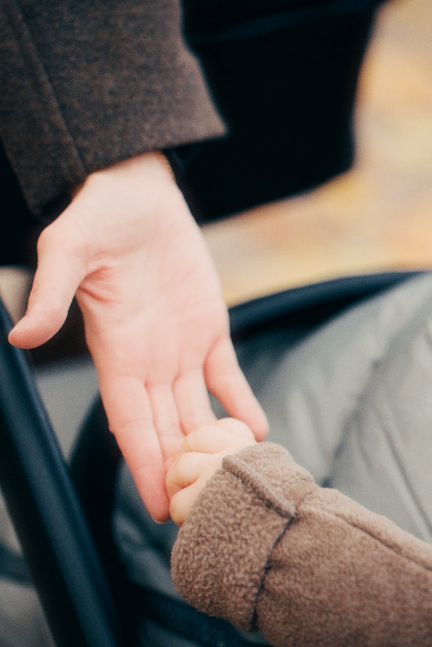 tender moment adult and child holding hands outdoors