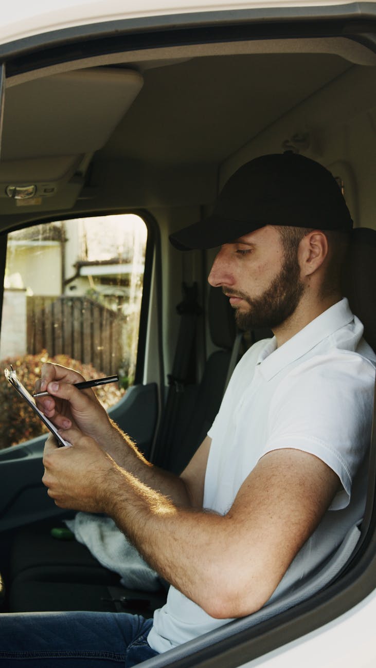 a man in white shirt holding a clipboard while in the van