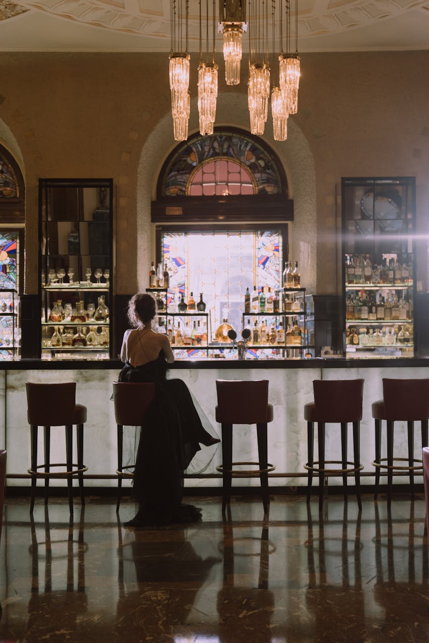woman in black dress sitting alone at the bar