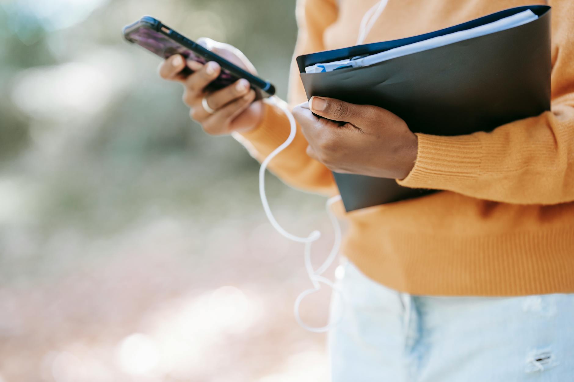 black woman with folder using smartphone