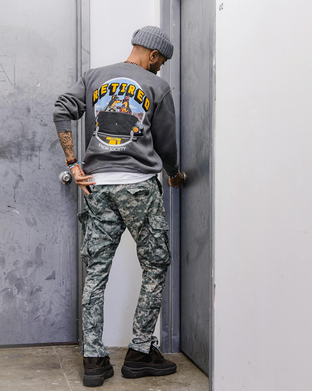 man wearing casual clothes with hand on doorknob