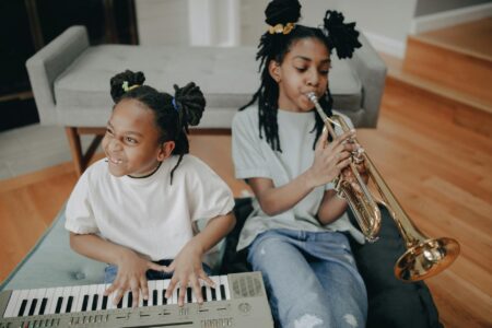 two girls happily playing musical instruments