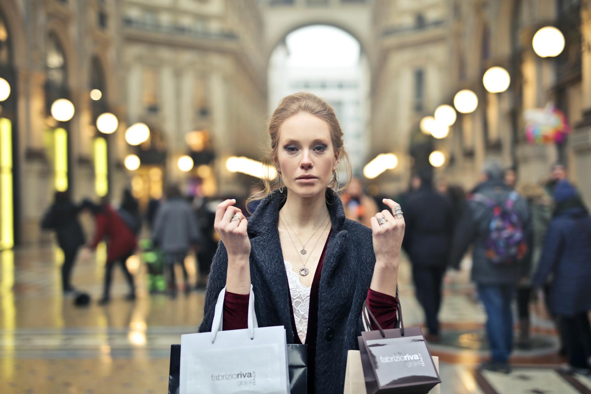 woman wearing black coat holding assorted color shopping bags on building