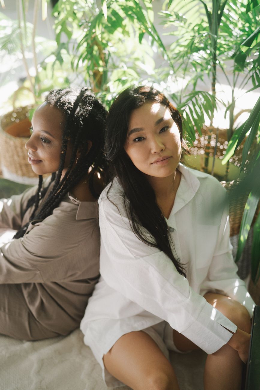 woman in white long sleeve shirt sitting beside green plant